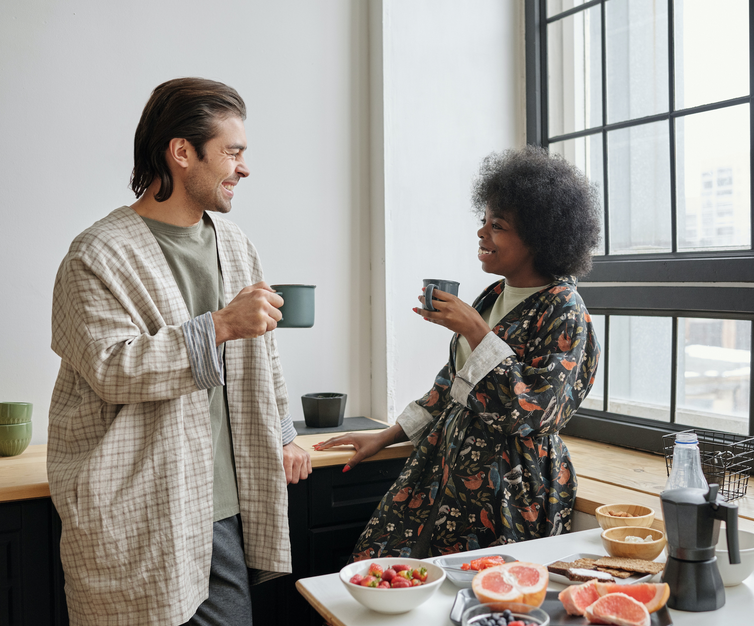 the owners of the shop looking at each other, smiling  with coffee mugs