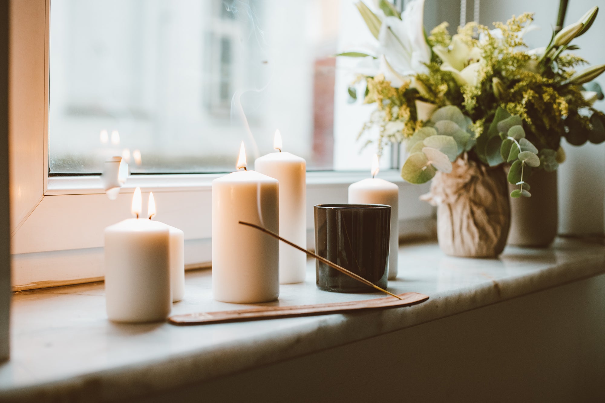 lit candles and incense on a window sill